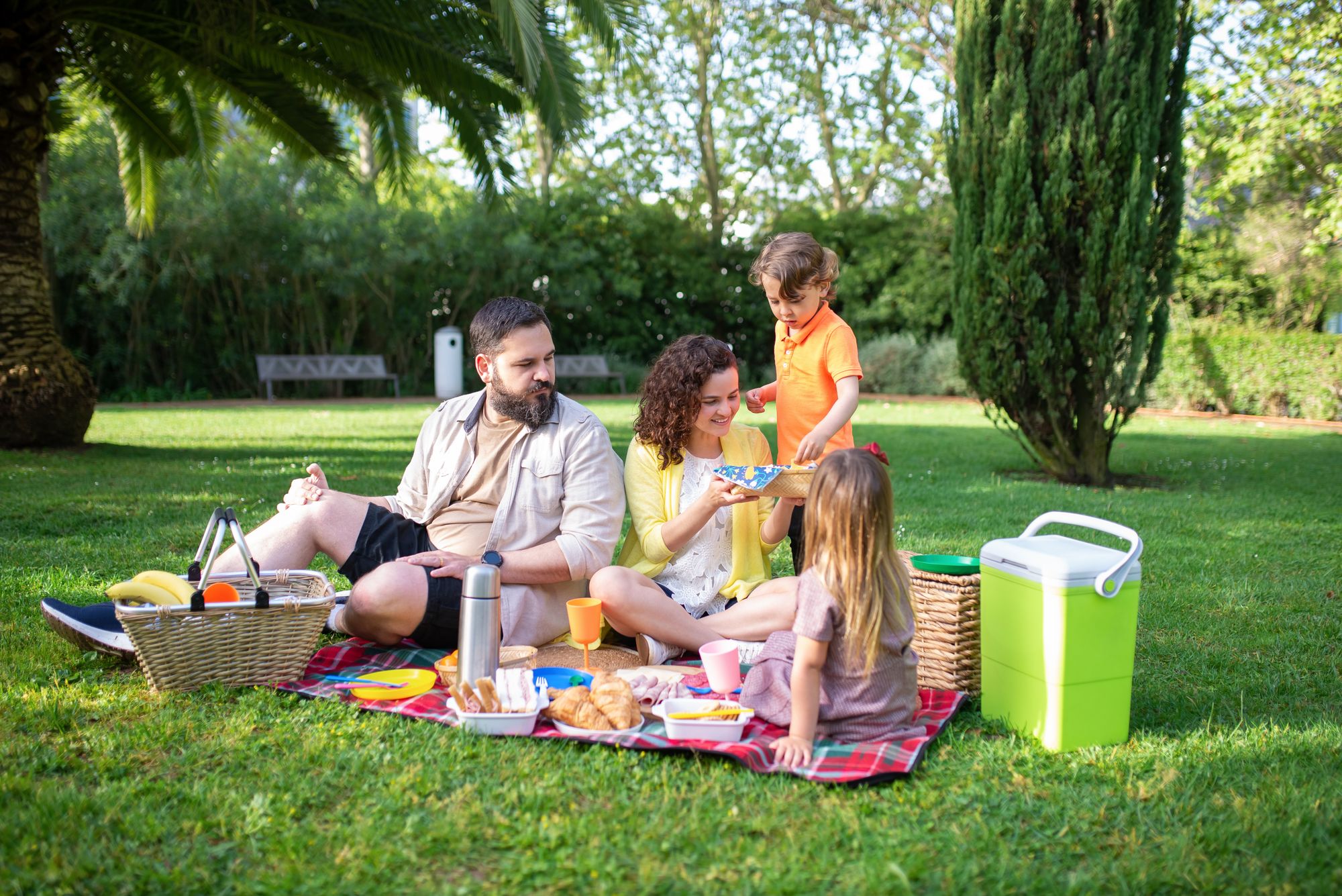 A family picnicking together on a sunny green park lawn